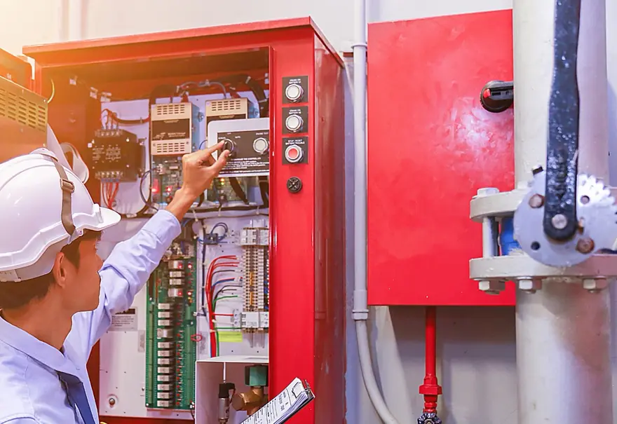 Technicien casqué contrôlant les organes d'une armoire de commande industrielle